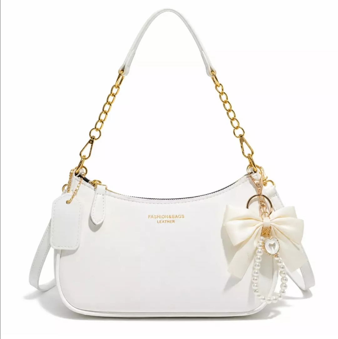 Elegant women’s shoulder bag with a modern and stylish design. Featuring a white finish, gold-tone chain strap, and a beautiful bow charm with pearl details. Versatile and perfect for everyday use, shopping, outings, dates, and special occasions. A lovely
